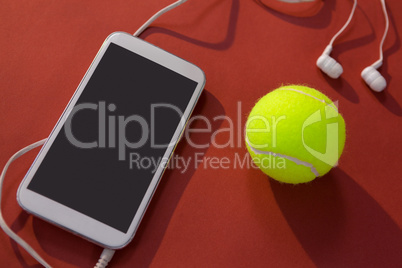 High angle view of tennis ball and mobile phone with in-ear headphones
