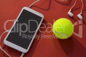 High angle view of tennis ball and mobile phone with in-ear headphones