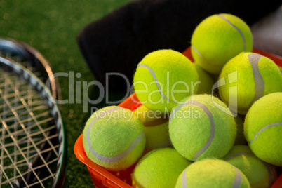 Close up of tennis balls in basket by rackets