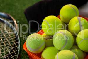 Close up of tennis balls in basket by rackets