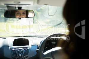 Woman looking into rear view mirror while driving a car