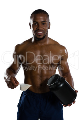 Portrait of shirtless male athlete holding supplement jar