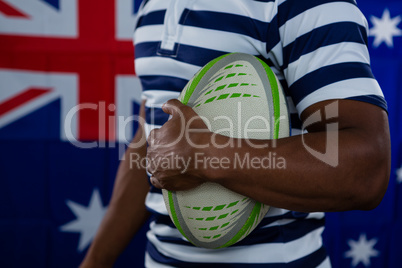 Mid section of male athlete holding rugby ball