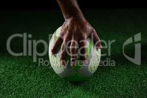 Cropped hand of sportsperson on rugby ball