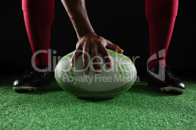 Low section of sportsperson on rugby ball