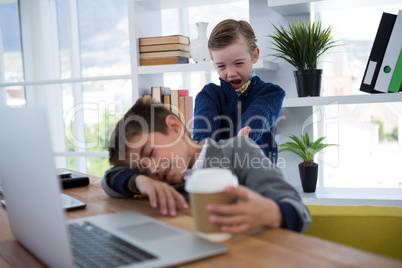 Boy as business executive sleeping while holding coffee cup