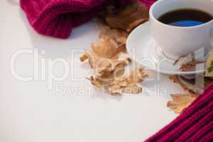 Cup of black tea with autumn leaves and woolen cloth