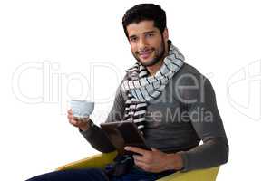 Portrait of man using digital tablet while having cup of tea