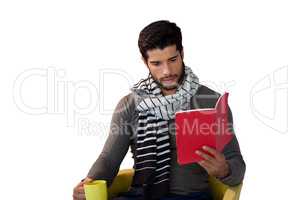 Man reading book while having coffee