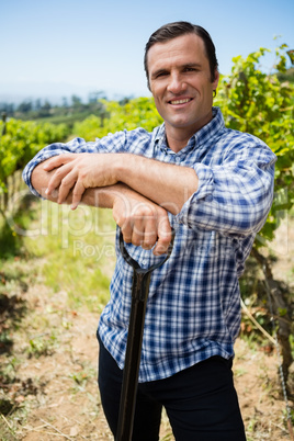 Portrait of smiling vintner standing with gardening equipment
