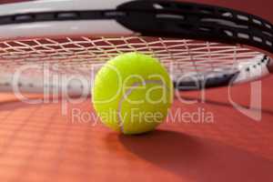 Close up of tennis racket leaning on ball