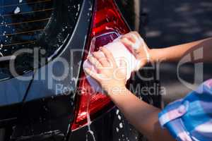 Teenage girl washing a car