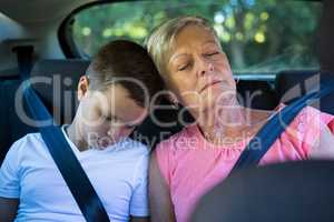 Grandmother and grandson relaxing in the back seat of car