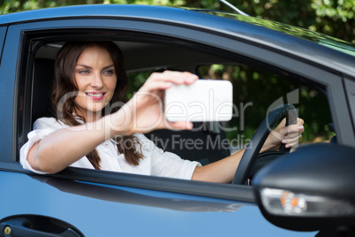 Woman taking selfie with mobile phone in car