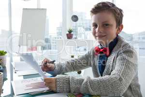 Boy as business executive holding document in office