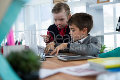 Kids as business executives discussing over laptop