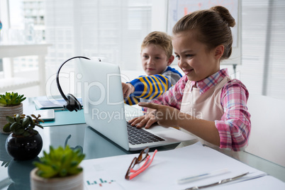 Kids as business executive interacting while using laptop