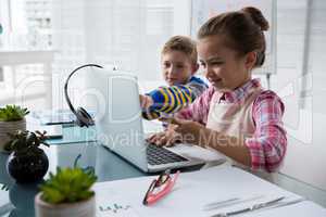 Kids as business executive interacting while using laptop