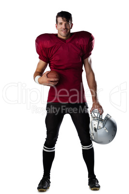 Portrait of smiling American football player holding ball and helmet