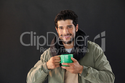 Smiling man holding a mug of coffee against black background