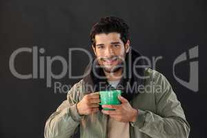 Smiling man holding a mug of coffee against black background