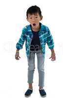 Astonished boy standing against white background