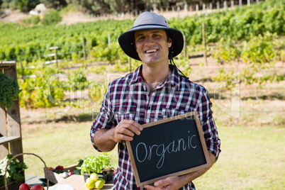 Portrait of happy man holding slate with text in vineyard