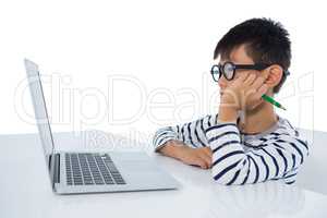 Boy sitting with laptop against white background