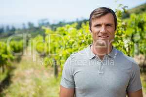 Portrait of smiling vintner standing in vineyard