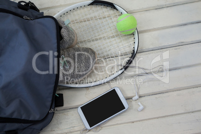 High angle view of gray bag on sports shoes with tennis gear by smartphone