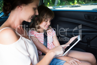 Mother and daughter using digital tablet in car