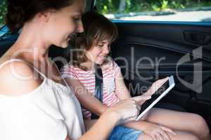 Mother and daughter using digital tablet in car