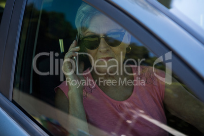 Senior woman talking on mobile phone in car