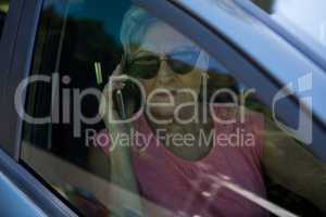 Senior woman talking on mobile phone in car