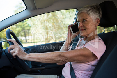 Senior woman talking on mobile phone in car