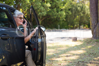 Senior woman talking on mobile phone in car