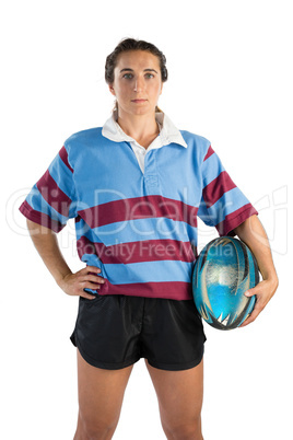 Portrait of confident female athlete with hand on hip holding rugby ball