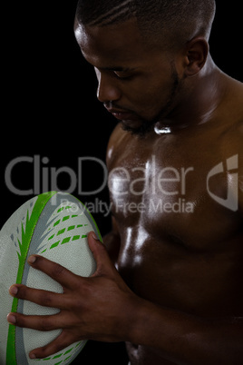 Close up of shirtless male rugby player holding ball