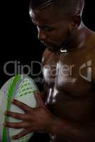 Close up of shirtless male rugby player holding ball