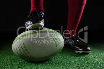 Low section of person stepping on rugby ball