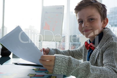 Boy as business executive holding document in office