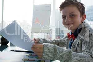 Boy as business executive holding document in office