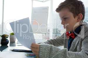 Boy as business executive verifying document