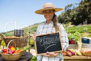 Portrait of happy woman holding slate with text in vineyard