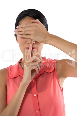 Woman covering her eyes with finger on lips against white background