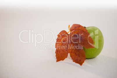 Close-up of green apple and autumn leaves