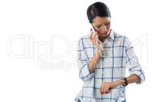 Female executive looking at her wristwatch while talking on the phone