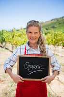 Portrait of happy woman holding slate with text in vineyard