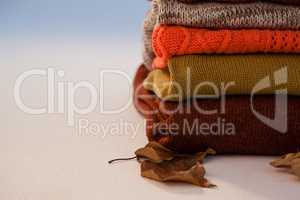 Stack of woolen clothing with autumn leaves