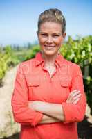 Smiling woman standing with hands on hip in vineyard